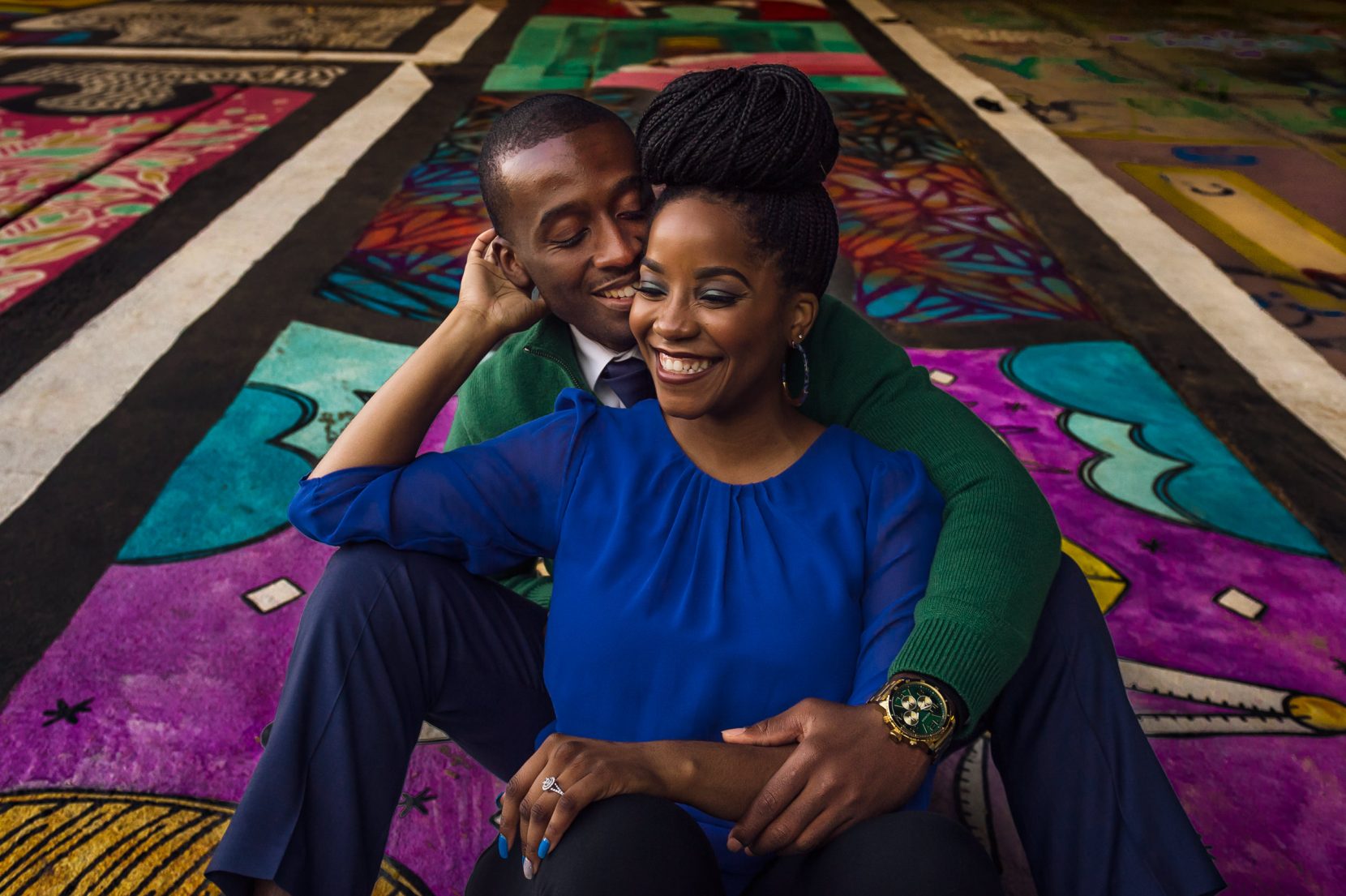 couple hugging and laughing sitting on graffiti under overpass in atlanta beltline