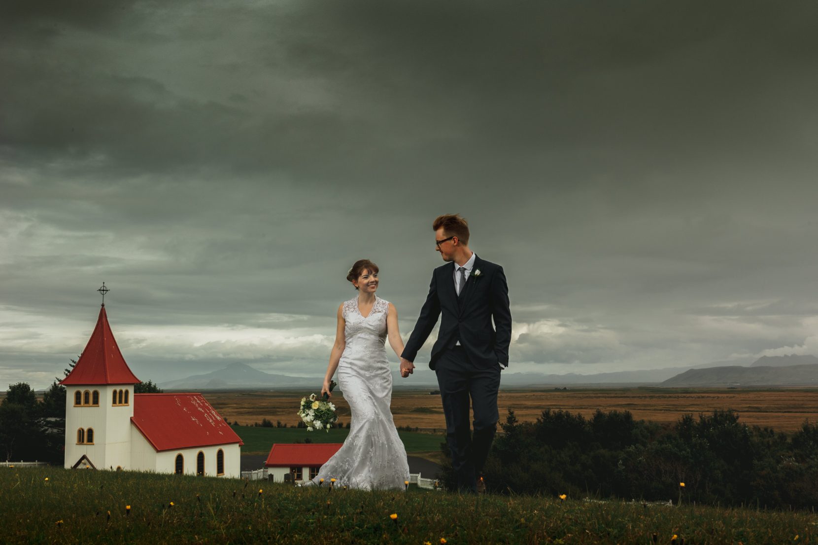 walking couple front of church storm clouds hella iceland outdoor