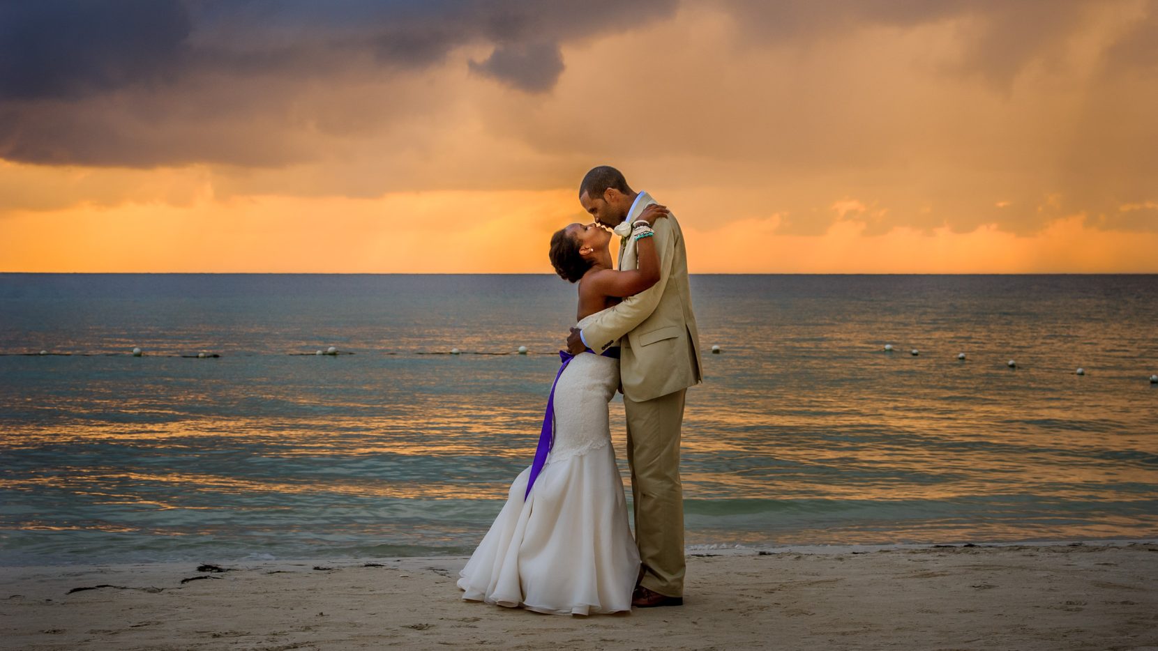 couple kissing in front of sunset on beach in Jamaica