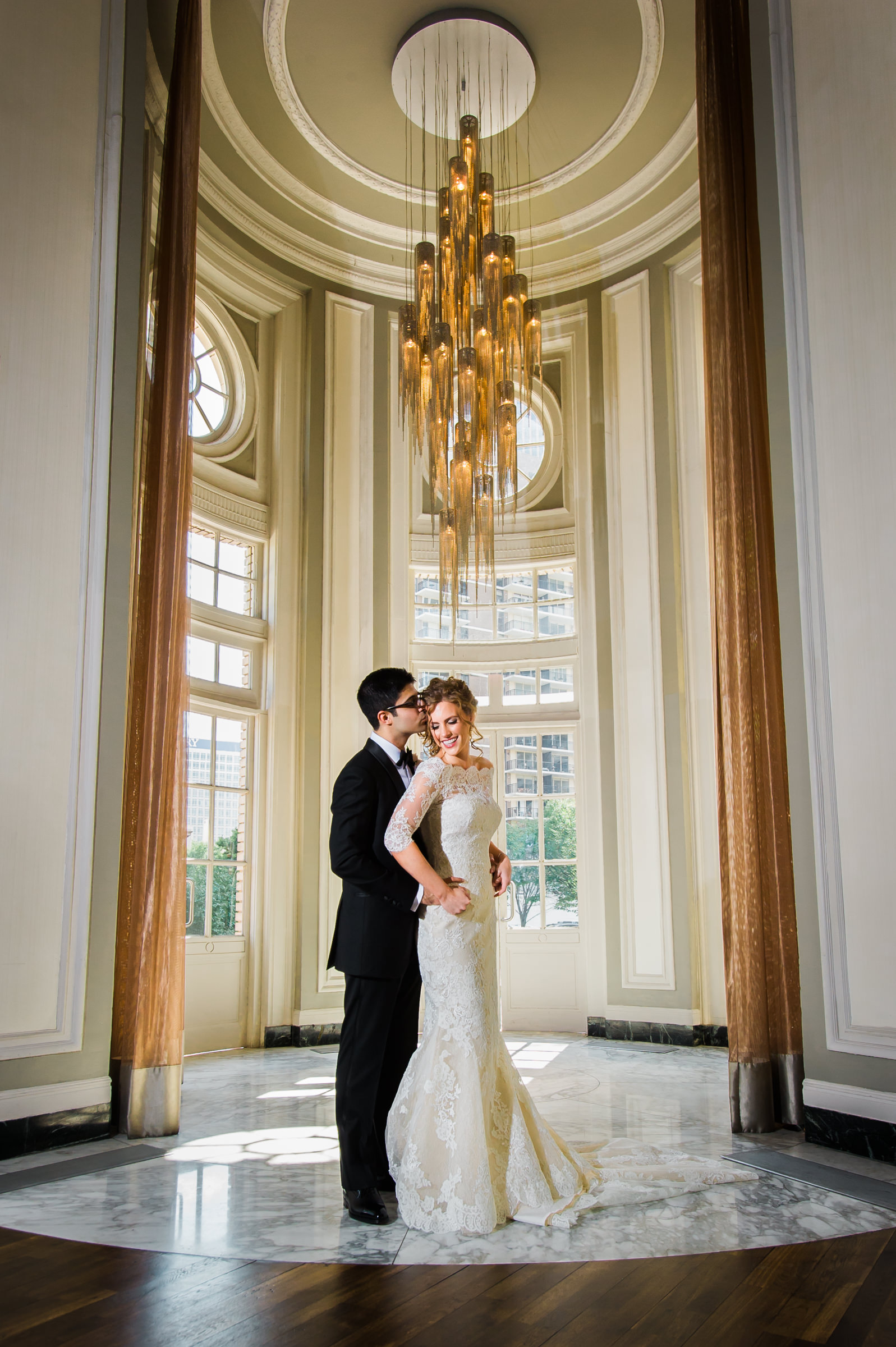 bride and groom under chandelier